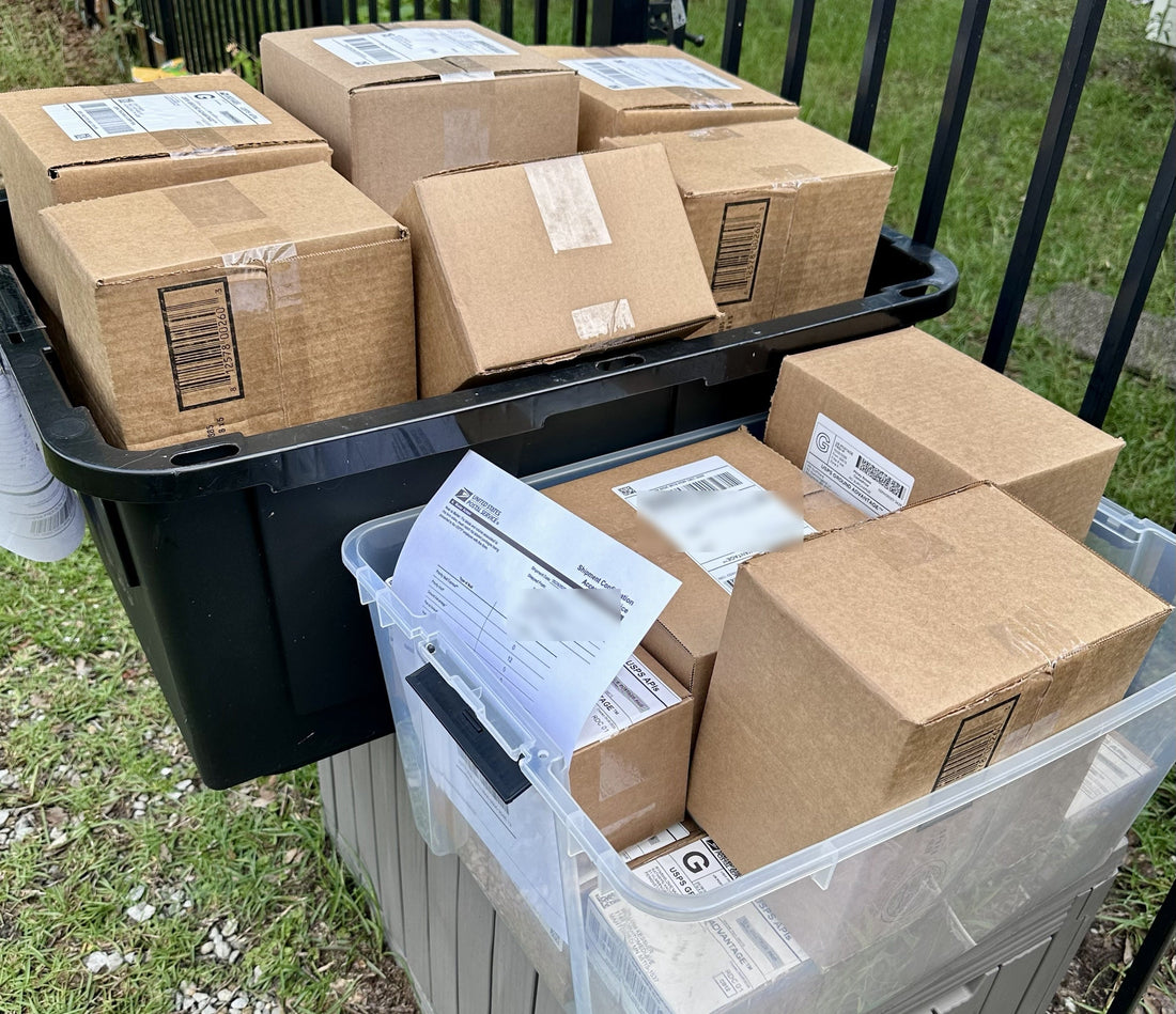 Stack of packed PM Outfitters hat orders ready for USPS Ground Advantage pickup