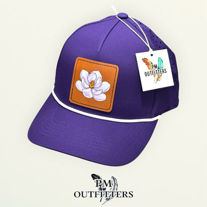 Hand-painted magnolia performance rope cap displayed with PM Outfitters branded hang tag