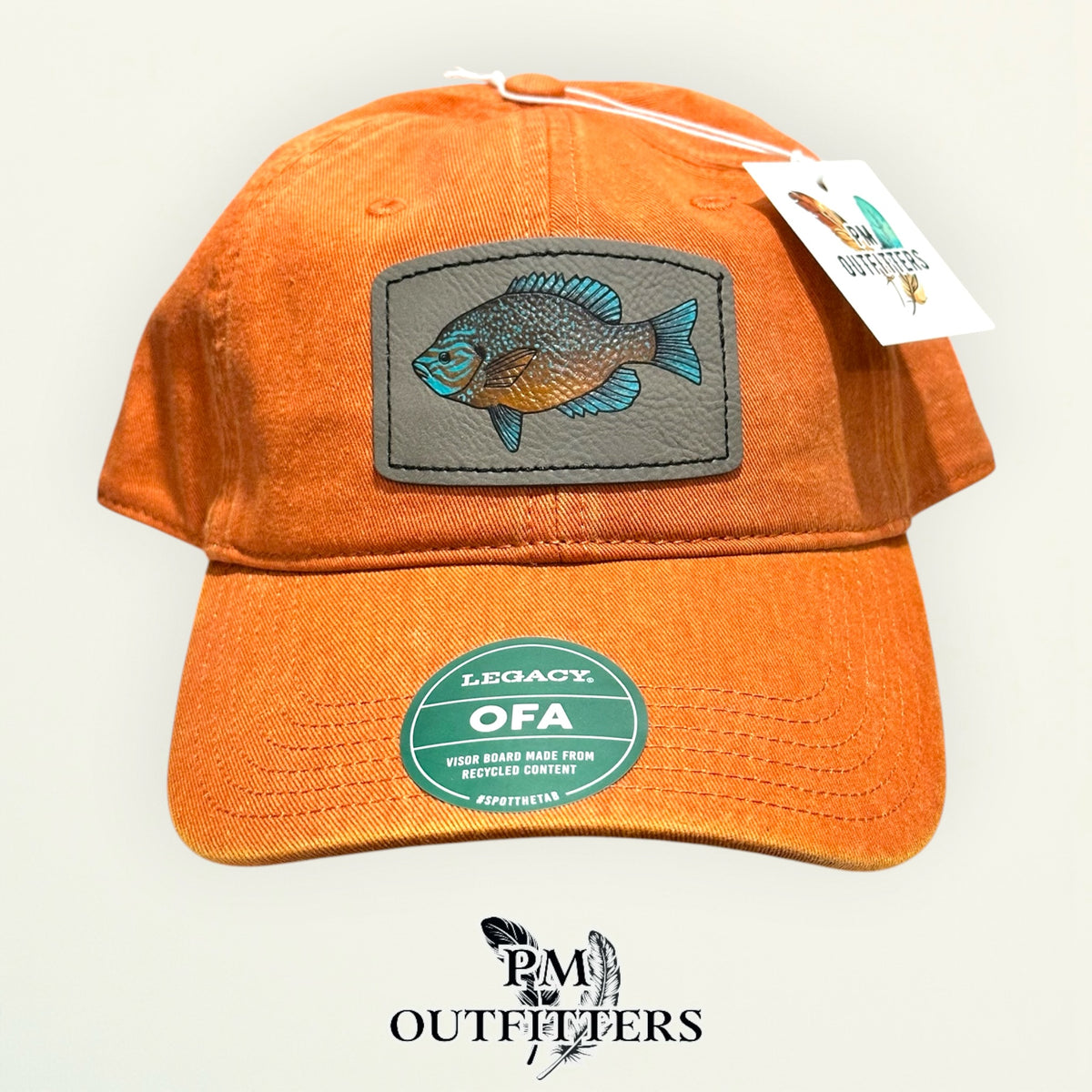 Hand-painted longear sunfish patch on a burnt orange Legacy garment-washed cap, PM Outfitters True Originals