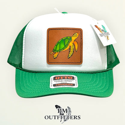 Hand-painted sea turtle trucker hat displayed with PM Outfitters branded hang tag