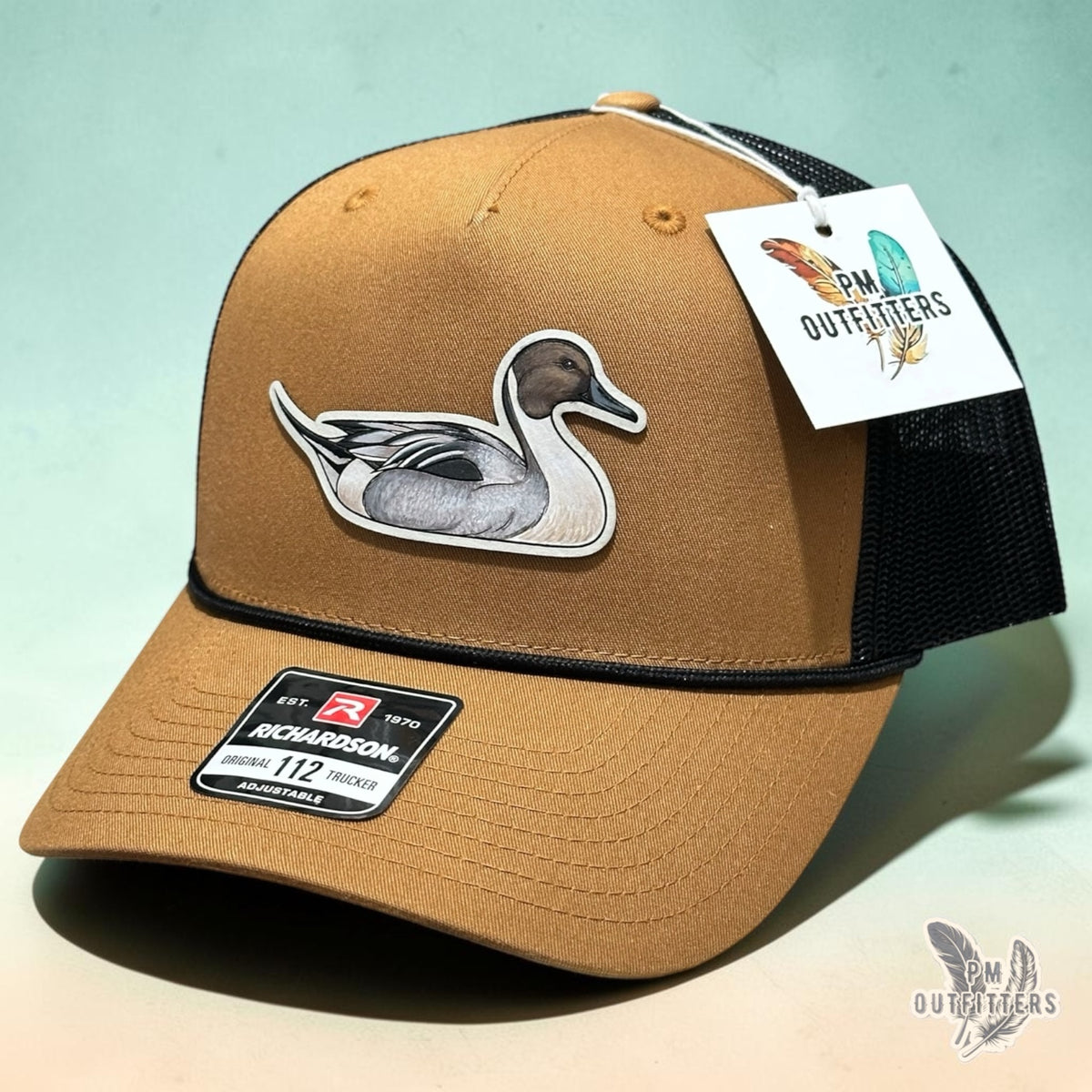Hand-painted Northern Pintail patch on a caramel and black Richardson 112 trucker hat, PM Outfitters True Originals