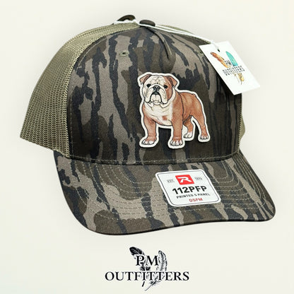 Mossy Oak Bottomland camo Richardson 112PFP trucker hat with hand-painted English Bulldog patch, angled view, PM Outfitters True Originals