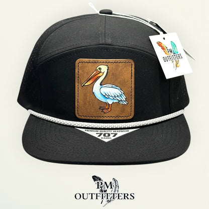 Side view of the hand-painted white pelican patch on the black Kamel 707 rope cap, PM Outfitters True Originals