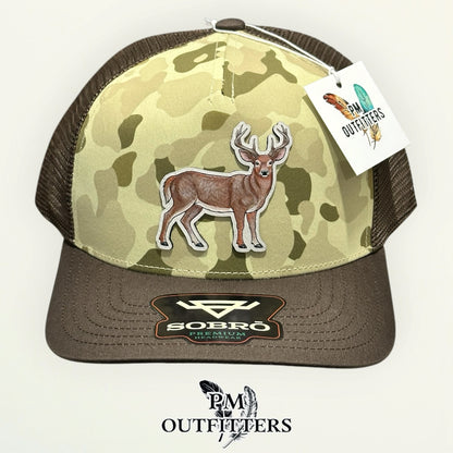 Hand-painted full-body whitetail buck on a light gray vegan leather patch, Ranchwood Camo trucker hat, PM Outfitters True Originals