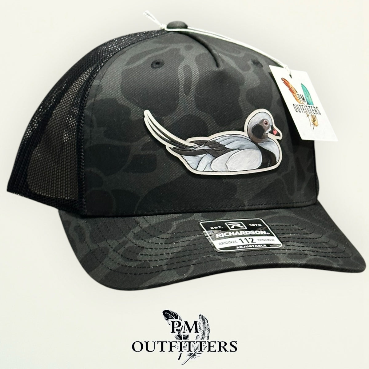 Sable duck camo Richardson 112PFP trucker hat with hand-painted Long-Tailed Duck patch, angled view, PM Outfitters True Originals