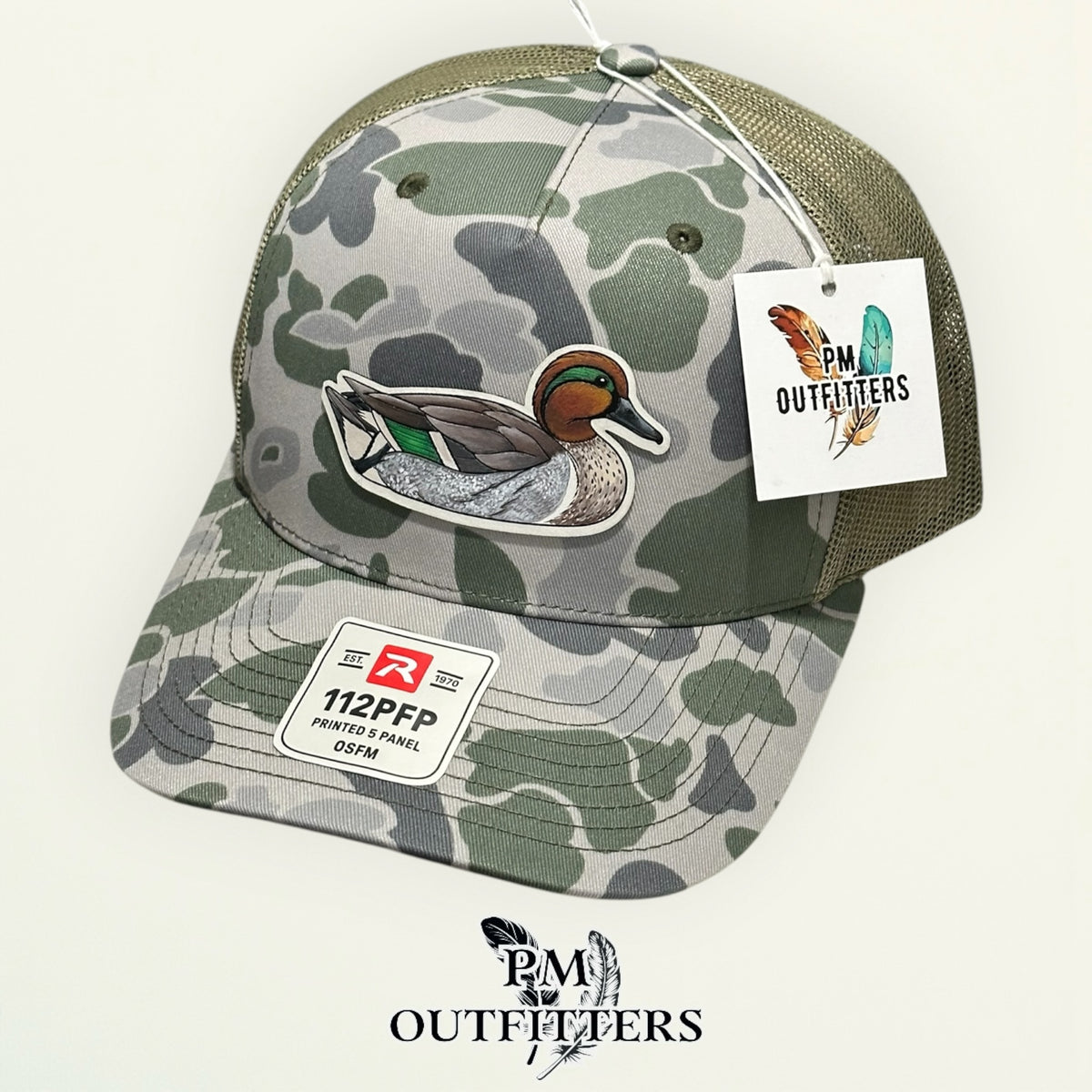 Hand-painted Green-Winged Teal trucker hat displayed with PM Outfitters branded hang tag