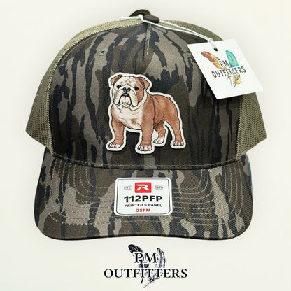 Side view of the hand-painted English Bulldog patch on the Mossy Oak Bottomland camo trucker hat, PM Outfitters True Originals