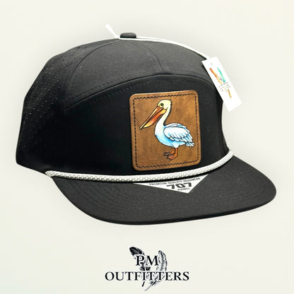 Black Kamel 707 performance rope cap with hand-painted white pelican patch, angled view, PM Outfitters True Originals