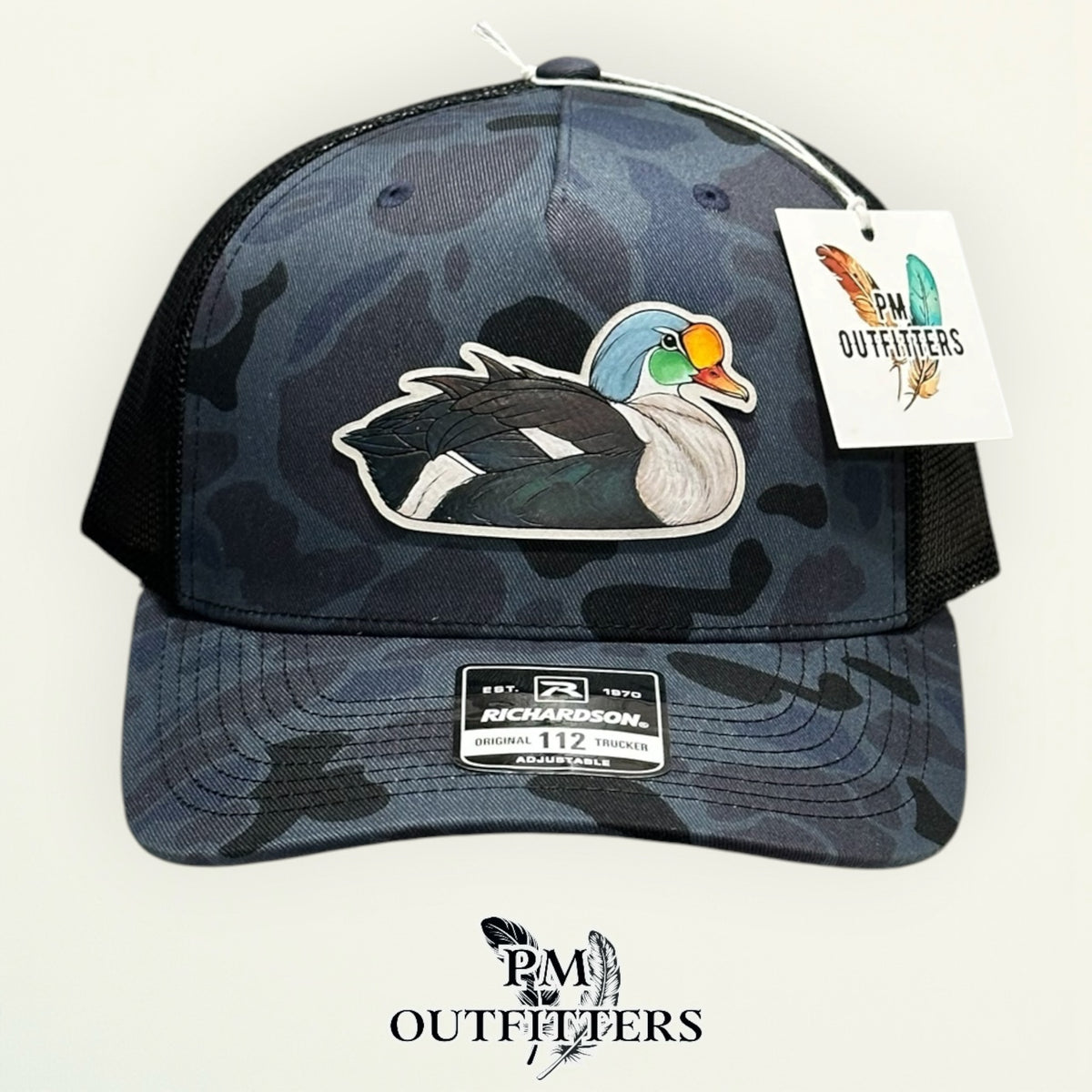 Side view of the hand-painted King Eider patch on the Admiral duck camo trucker hat, PM Outfitters True Originals