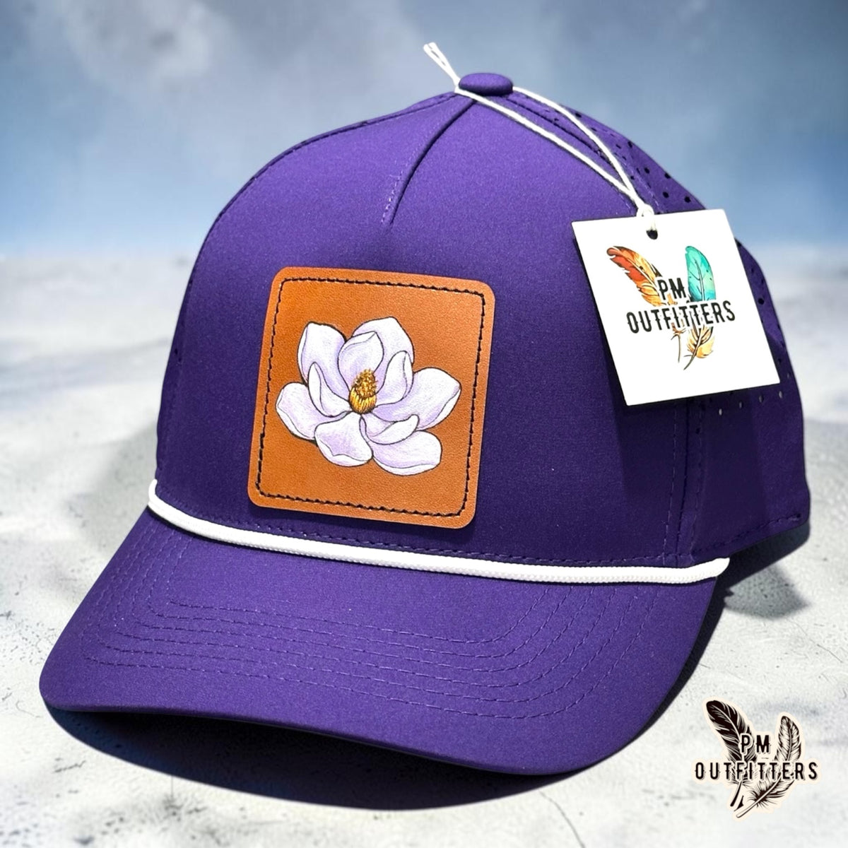 Hand-painted magnolia bloom patch on a purple Outdoor Cap OC551PF performance rope cap, PM Outfitters True Originals