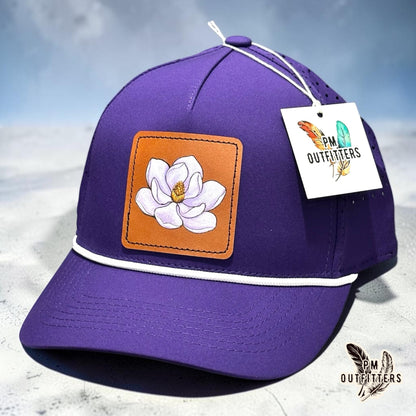Hand-painted magnolia bloom patch on a purple Outdoor Cap OC551PF performance rope cap, PM Outfitters True Originals