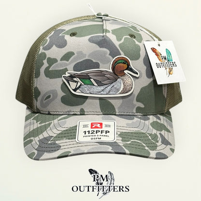 Side view of the hand-painted Green-Winged Teal patch on the Marsh duck camo trucker hat, PM Outfitters True Originals