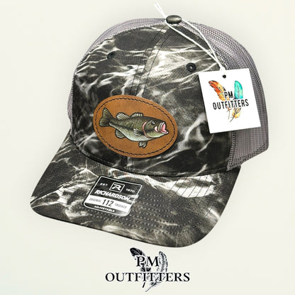 Hand-painted largemouth bass camo trucker hat displayed with PM Outfitters branded hang tag