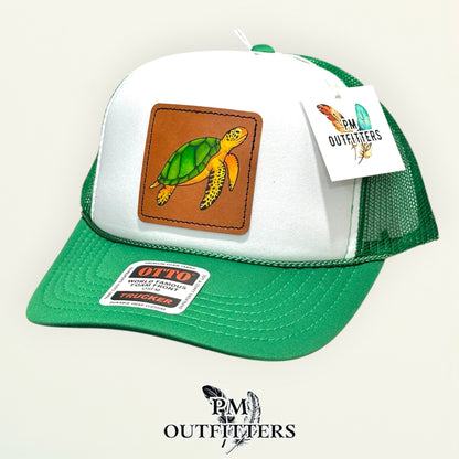 White and green Otto foam front trucker hat with hand-painted sea turtle patch, angled view, PM Outfitters True Originals