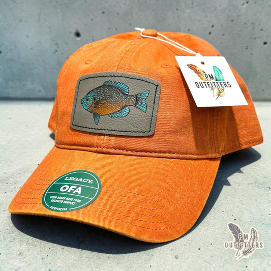 Hand-painted longear sunfish patch on a burnt orange Legacy garment-washed cap, PM Outfitters True Originals