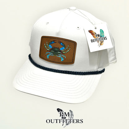 Hand-painted blue crab patch on a white Richardson 258 rope trucker hat with navy trim, PM Outfitters True Originals