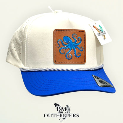 Cream and royal blue Dallas 804 performance rope cap with hand-painted octopus patch, angled view, PM Outfitters True Originals
