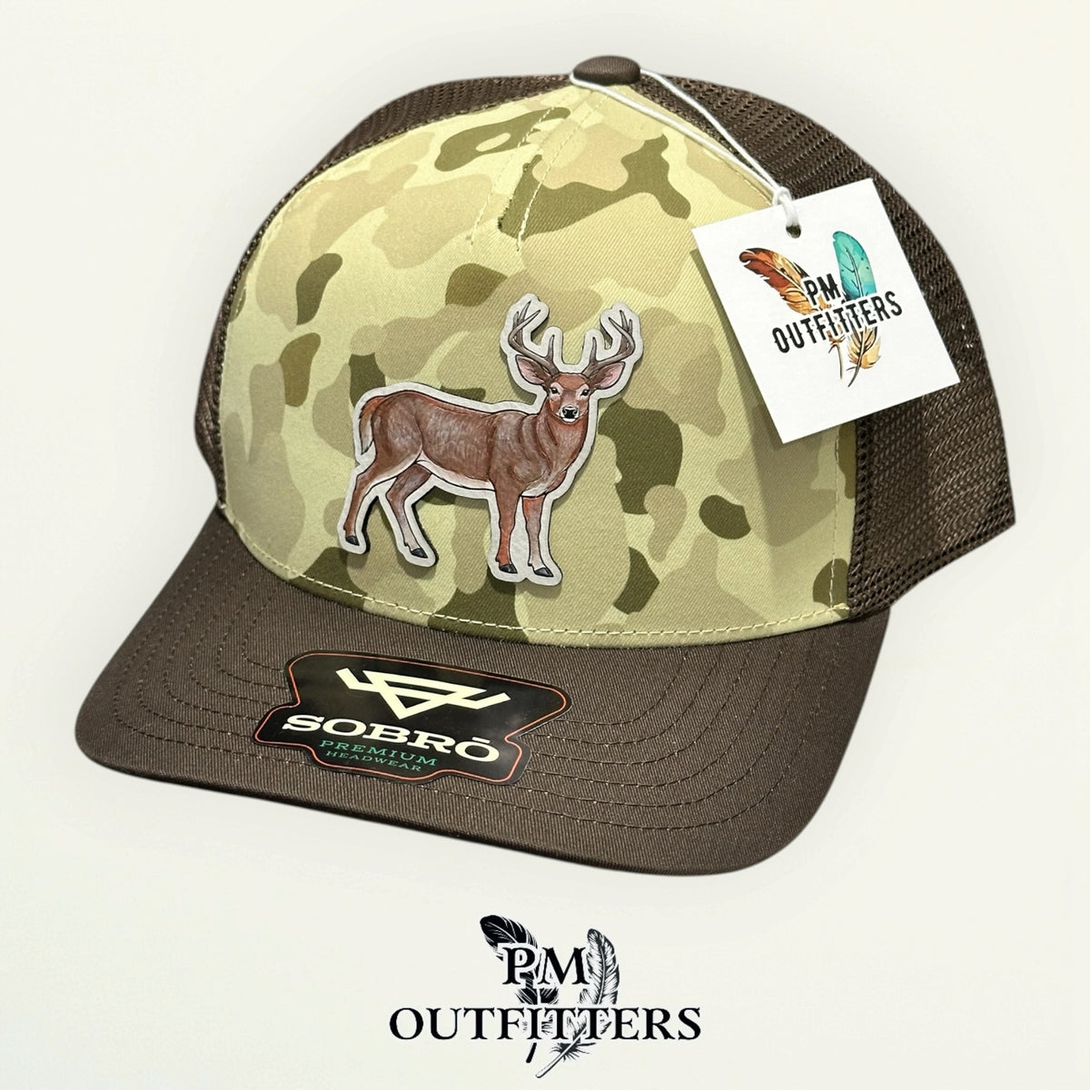 Hand-painted whitetail buck trucker hat in Ranchwood Camo with PM Outfitters hang tag