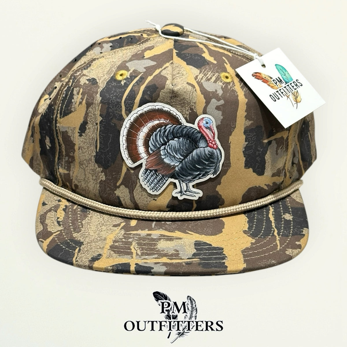 Hand-painted tom turkey patch on a light gray vegan leather patch, Sobro HuntLand camo rope hat, PM Outfitters True Originals