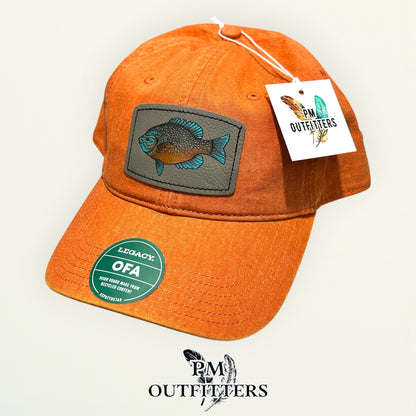 Hand-painted longear sunfish patch on a burnt orange Legacy garment-washed cap, PM Outfitters True Originals