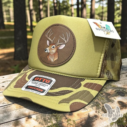 Hand-painted whitetail buck patch on an olive green and camo Otto foam front trucker hat, PM Outfitters True Originals
