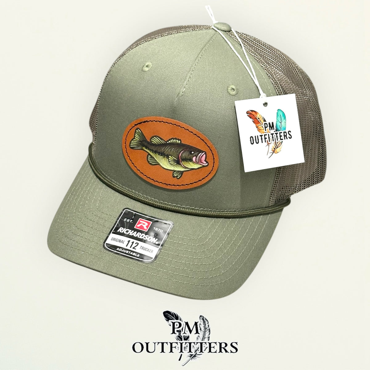 Hand-painted largemouth bass trucker hat displayed with PM Outfitters branded hang tag