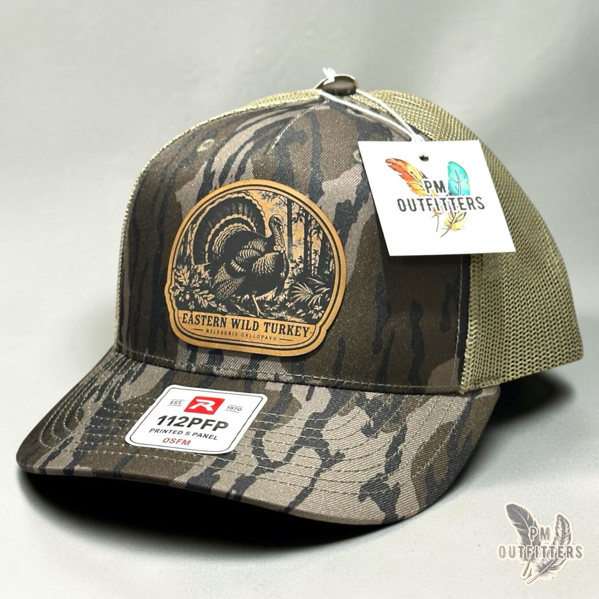 Eastern Wild Turkey leather patch hat on Richardson 112PFP Mossy Oak Bottomland camo – angled front view